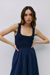 woman wearing a navy blue sleeveless dress with a fitted bodice and a flared skirt