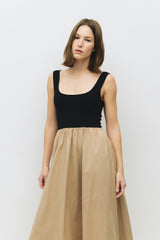 woman wearing a black sleeveless top with a scoop neckline and a beige flowy skirt
