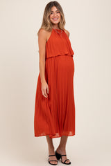 woman wearing a rust pleated maternity dress with a flowy silhouette and a visible baby bump