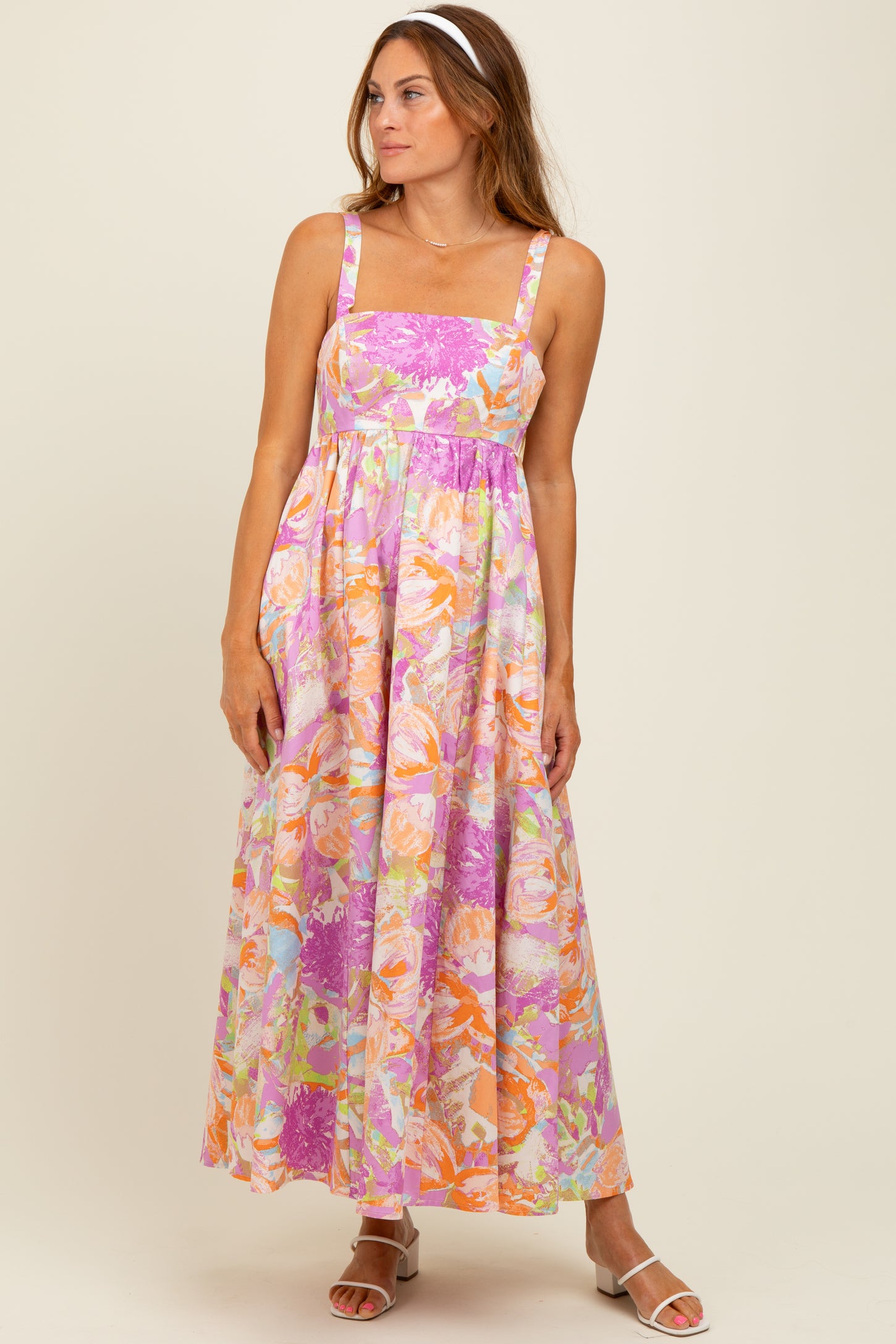 woman wearing a floral maxi dress in pink, orange, and lavender with a square neckline and spaghetti straps