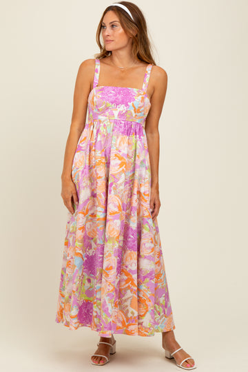 woman wearing a floral maxi dress in pink, orange, and lavender with a square neckline and spaghetti straps