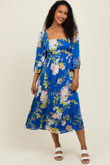 woman wearing a blue floral midi dress with puff sleeves and a square neckline