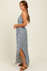 woman wearing a blue floral maxi dress with a side slit and spaghetti straps, standing in profile