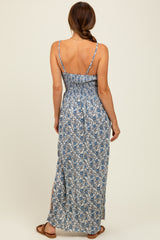 woman wearing a blue and white floral maxi dress with a smocked back and side slits, showing a back view
