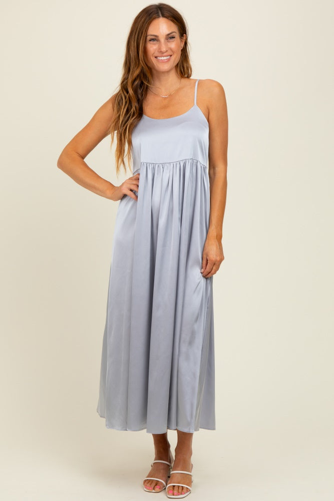 woman wearing a light blue satin maxi dress with a fitted bodice and flowing skirt, standing and smiling