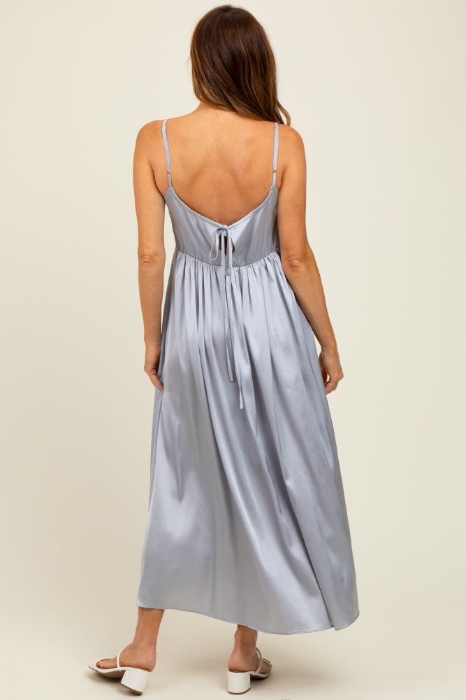 woman wearing a pale blue satin maxi dress with a tie-back detail and spaghetti straps