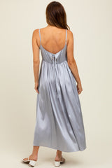 woman wearing a pale blue satin maxi dress with a tie-back detail and spaghetti straps