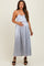 woman wearing a light gray satin maternity dress with a fitted bodice and flowing skirt, gently holding her baby bump