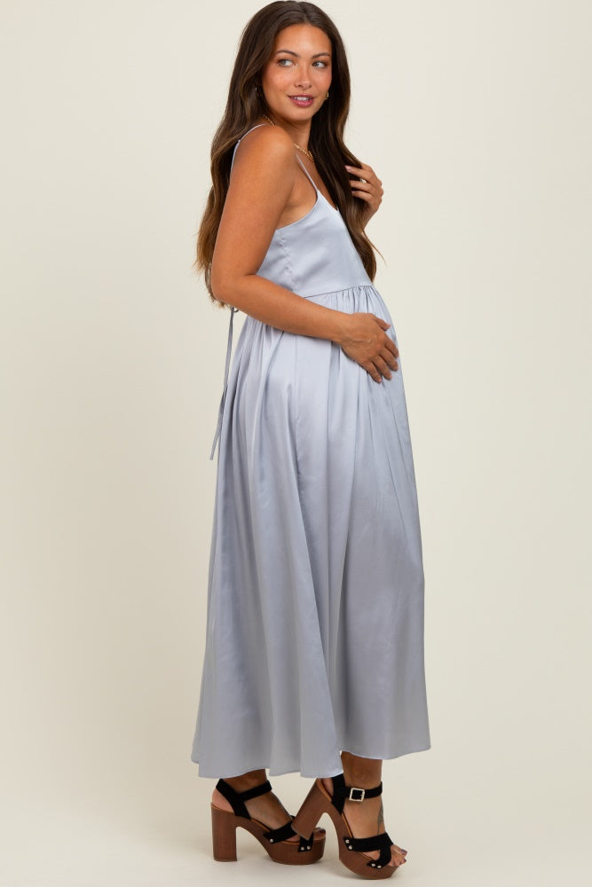 woman wearing a light blue maternity maxi dress and holding her baby bump