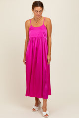 woman wearing a bright pink sleeveless maxi dress with a gathered waist and thin straps