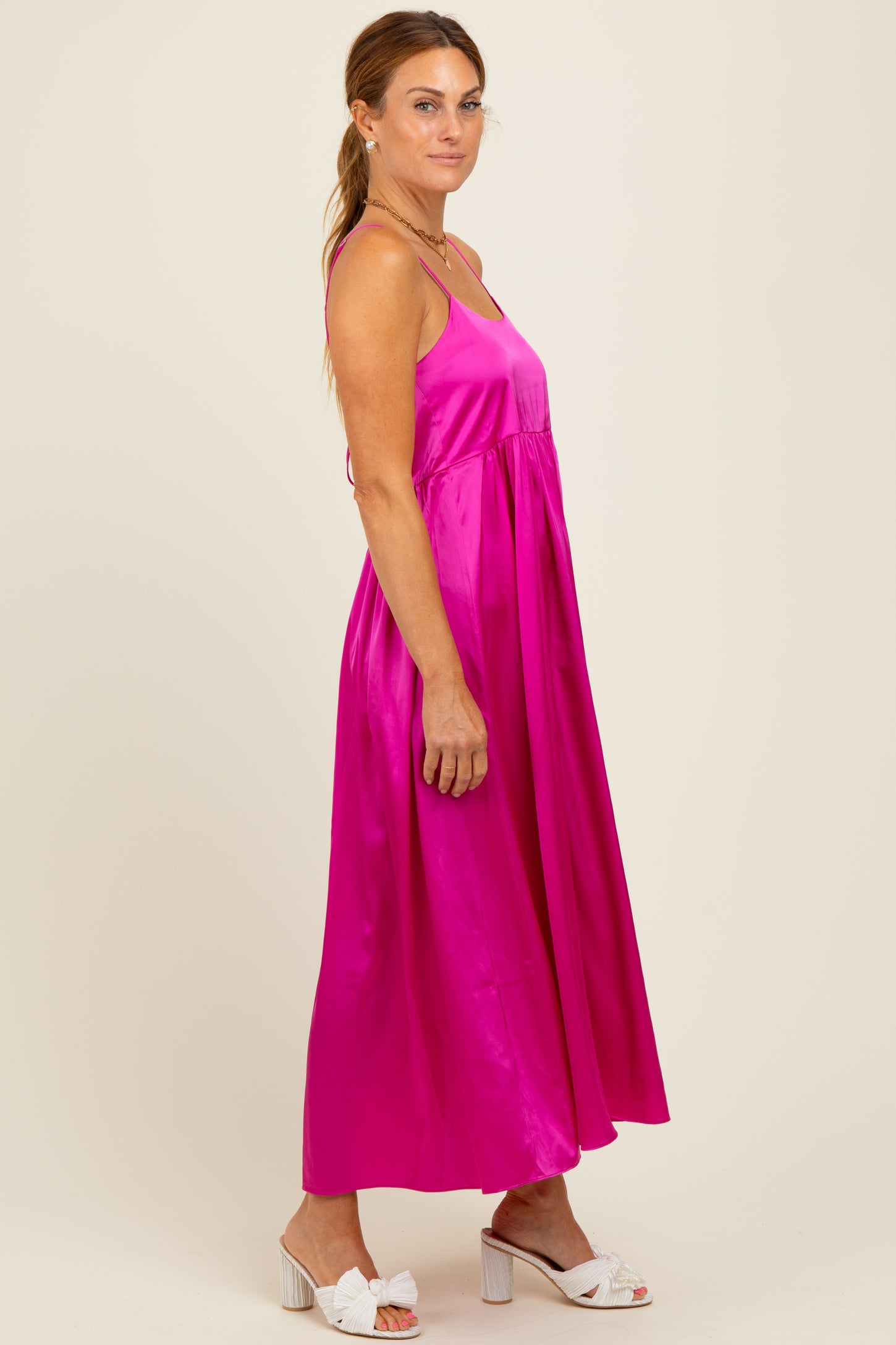 woman wearing a bright pink satin maxi dress with adjustable straps and a flowing silhouette