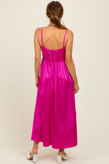 woman wearing a back view of a bright pink satin maxi dress with adjustable straps and a tie closure at the back
