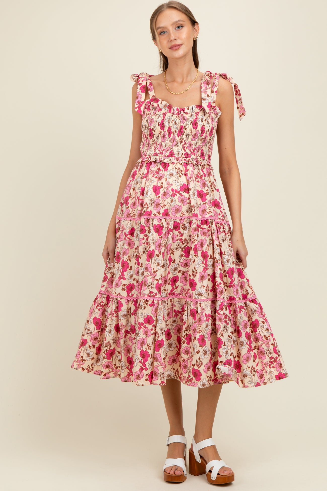 woman wearing a pink floral maternity dress with tie straps and a ruffled hemline