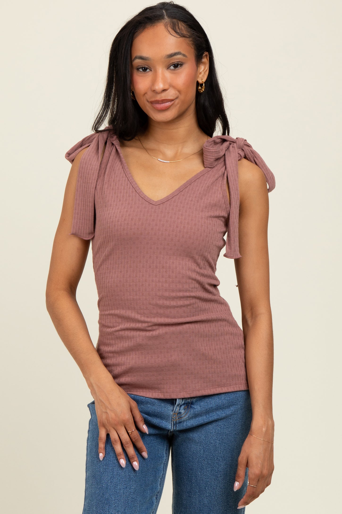 woman wearing a mauve ribbed tank top with tie shoulder details and a v-neck, paired with blue jeans