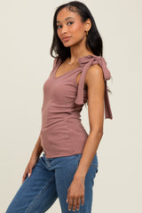woman wearing a mauve ribbed top with v-neck and tied shoulder straps, paired with light blue jeans