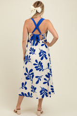 woman wearing a white maternity dress with blue leaf print and a tie-back detail, showing her baby bump from the back