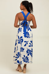 woman wearing a white and blue floral print maxi dress with a halter neck and open back design