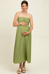 woman wearing a light green strapless maternity maxi dress and holding her baby bump