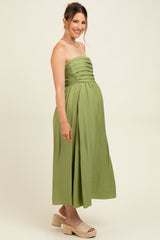woman wearing a sage green strapless maternity dress with pleated detailing, showcasing her baby bump