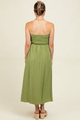 woman wearing a green maternity maxi dress with a smocked bodice and flowy skirt, viewed from the back