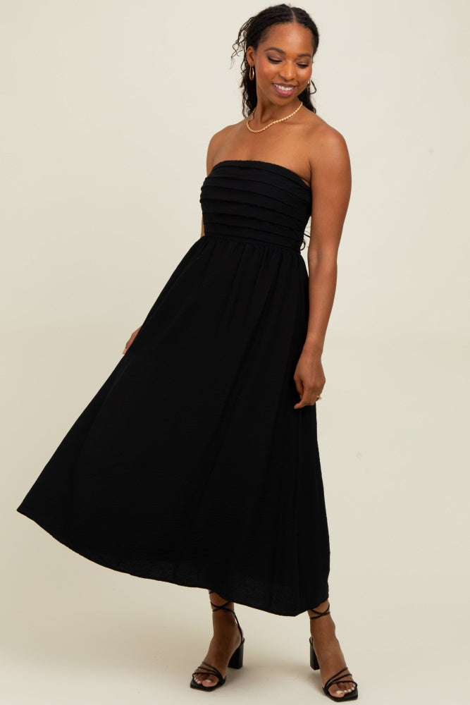 woman wearing a black strapless maxi dress with ruching at the bust and a flowy skirt