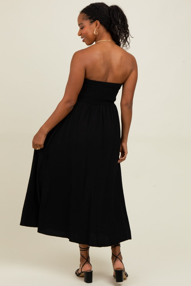 woman wearing a black strapless maxi dress with a smocked bodice and flowing skirt, viewed from the back