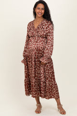 woman wearing a brown leopard print maternity dress with long sleeves and ruffled hem, showcasing her baby bump