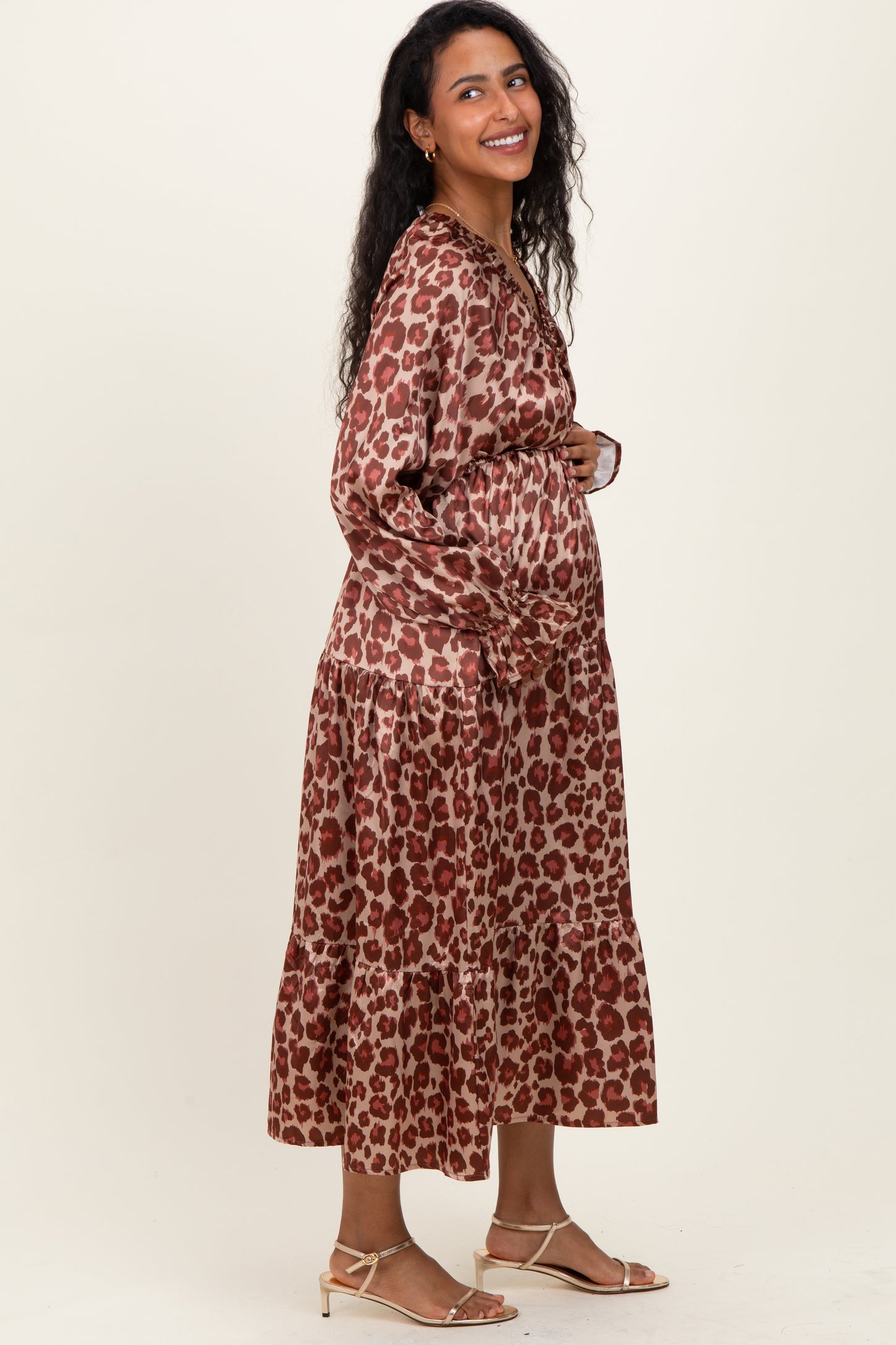 woman wearing a brown leopard print maternity dress with a tiered skirt and showing her baby bump