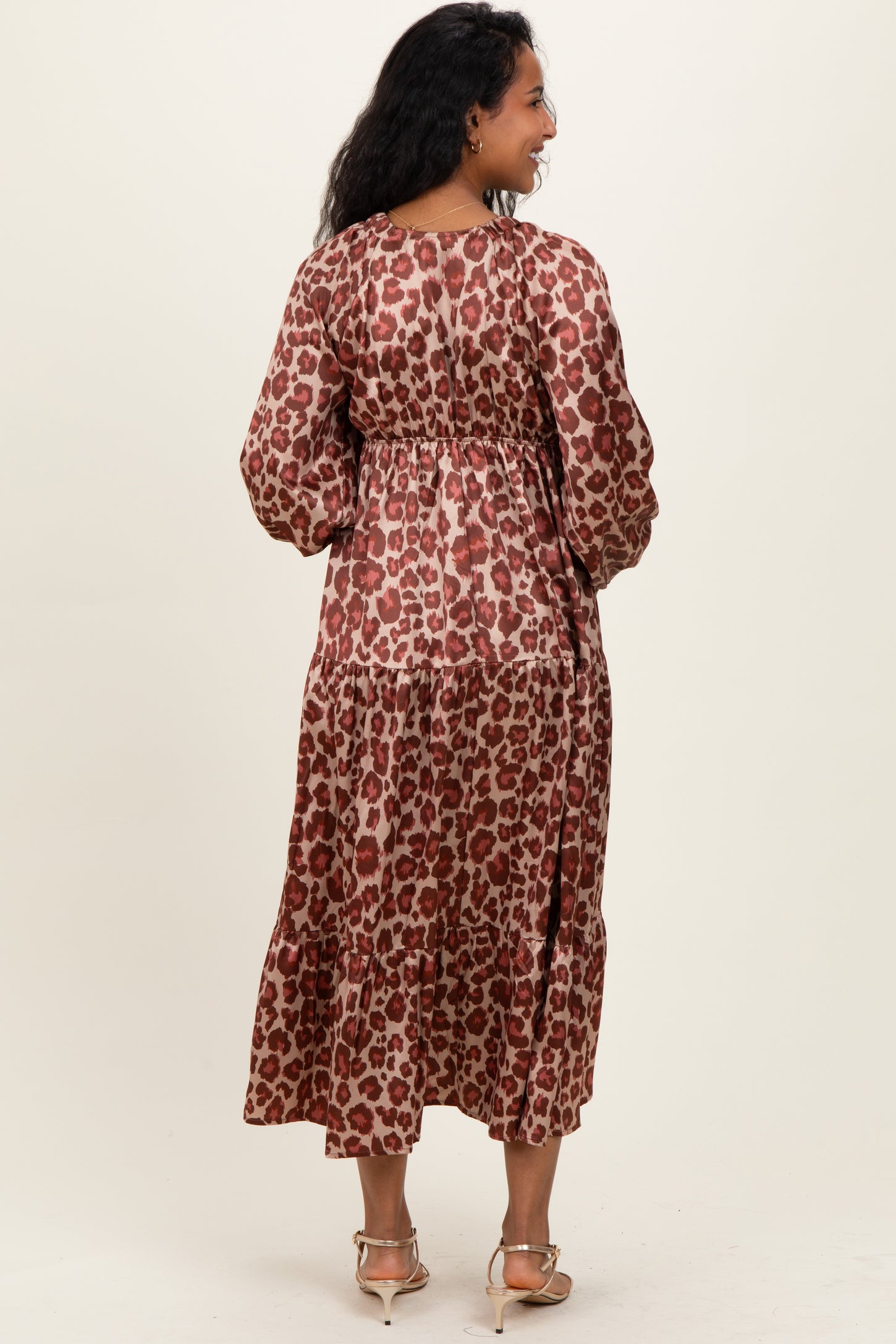 woman wearing a brown and red leopard print maternity dress with a tiered skirt and long sleeves