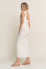 woman wearing a white ribbed knit sleeveless midi dress with a scoop back, paired with beige slide sandals