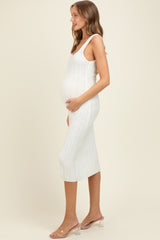 woman wearing a white ribbed knit maternity dress with a fitted silhouette and holding her baby bump