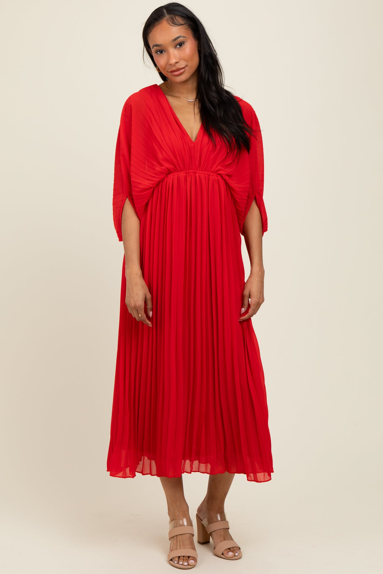 woman wearing a red pleated maxi dress with a deep v-neck and kimono sleeves
