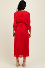 woman wearing a red pleated midi dress with long sleeves and a cinched waist, viewed from the back