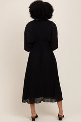 woman wearing a black pleated midi dress with a flowy silhouette and short sleeves, seen from the back