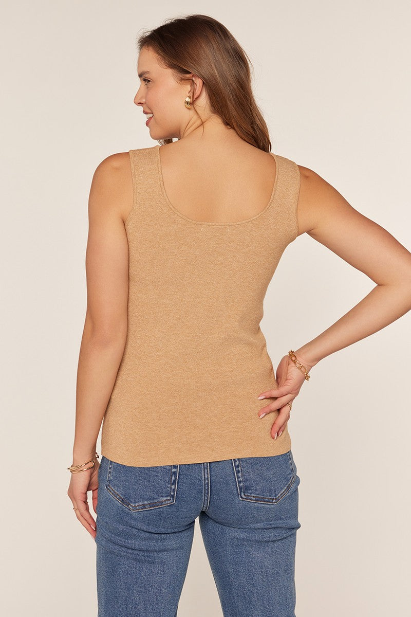 woman wearing a light brown sleeveless top and blue high-waisted jeans, seen from the back