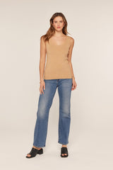 woman wearing a soft tan sleeveless top and blue high-waisted flared jeans with open-toe black heels