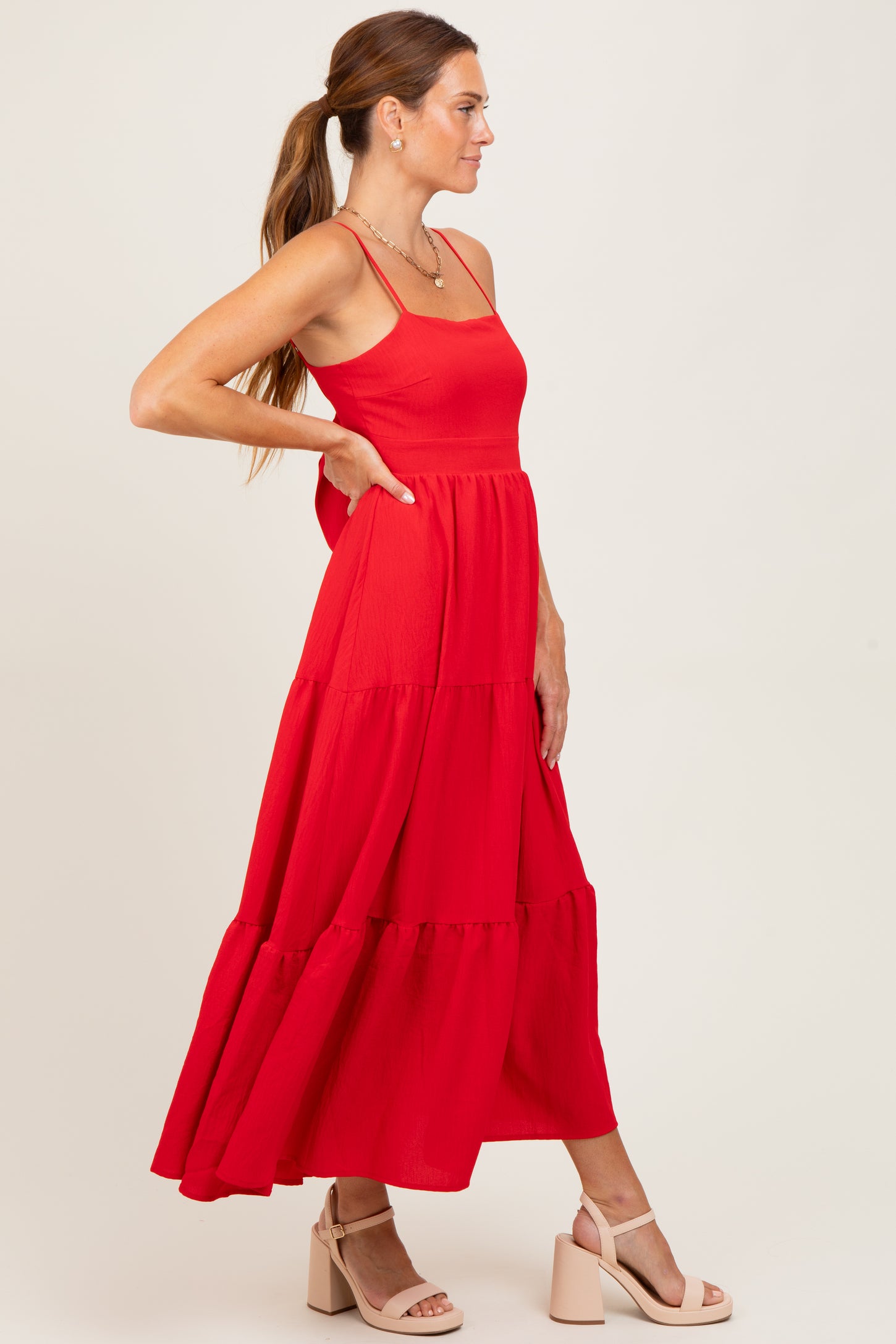 woman wearing a red tiered maxi dress with spaghetti straps and a flowy silhouette