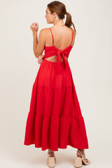 woman wearing a red tiered maxi dress with a tied back detail and open back design