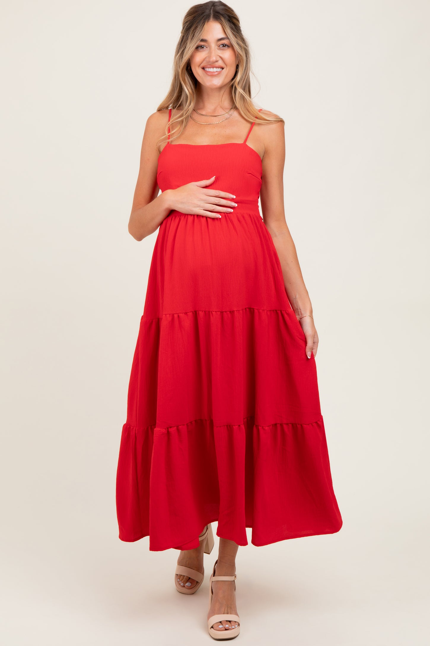 woman wearing a red tiered maternity dress and holding her baby bump