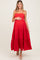 woman wearing a red tiered maternity dress and holding her baby bump