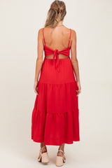 woman wearing a red tiered maternity dress with a tied back detail, showing off her baby bump