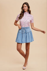 woman wearing a pink floral short sleeve blouse and a light blue denim skirt with a drawstring waist