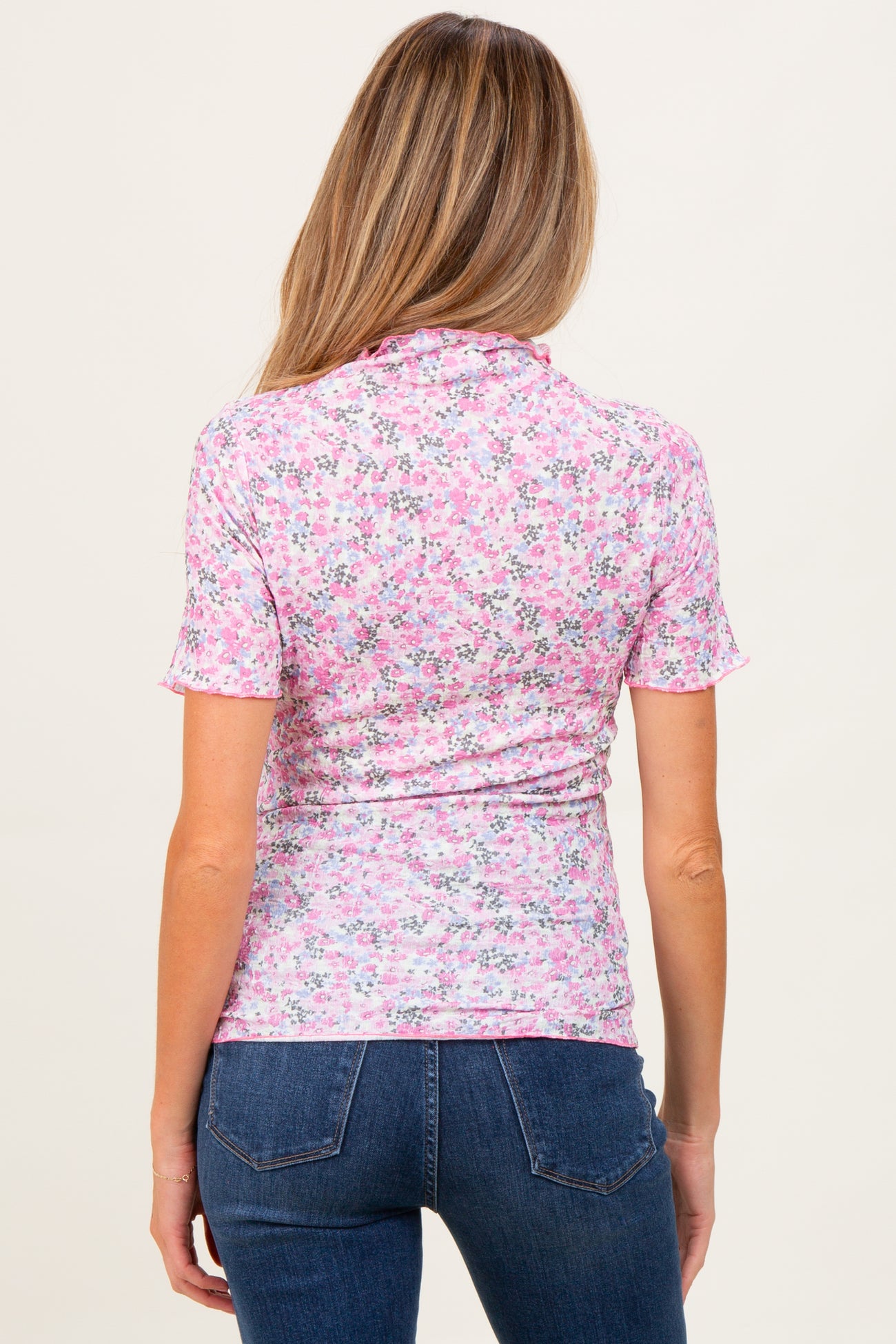 woman wearing a pink floral print maternity top with short sleeves and a fitted silhouette