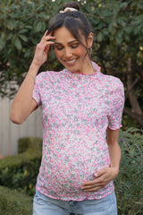 woman wearing a pink floral maternity top and holding her baby bump