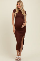 woman wearing a brown short sleeve maternity dress with side ruching and a slit, holding her baby bump