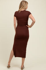 woman wearing a brown short sleeve maternity dress with a fitted silhouette and a side slit, showing her back