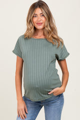 woman wearing an olive green ribbed maternity top and showing her baby bump while smiling