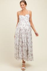 woman wearing a white floral maternity maxi dress with adjustable straps and a gathered waist, showcasing her baby bump