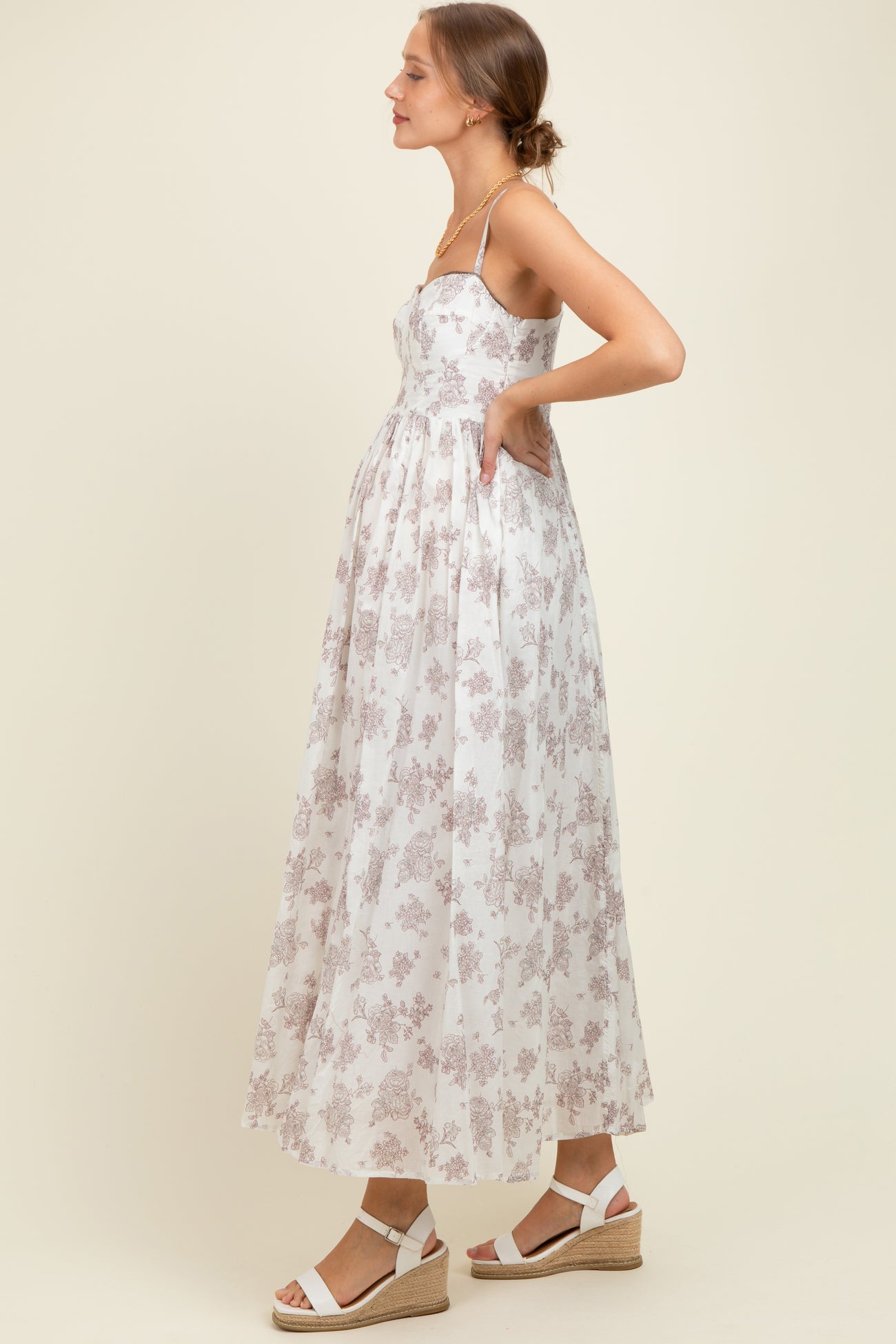 woman wearing a floral print maternity maxi dress with a fitted bodice and flowy skirt, showing a baby bump