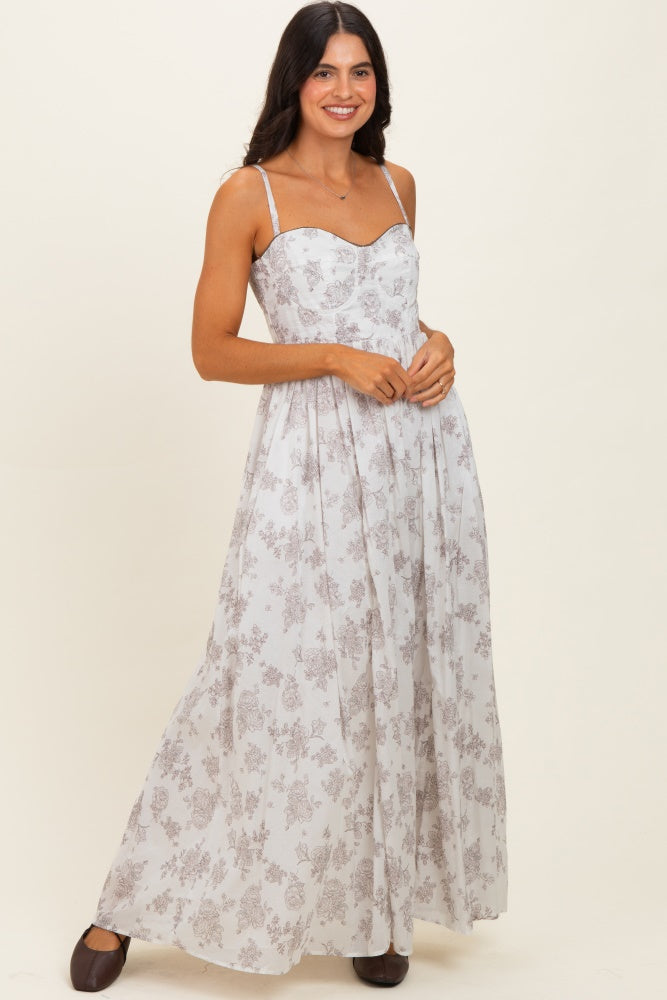 woman wearing a white floral maxi dress with thin straps and a fitted bodice, standing and smiling